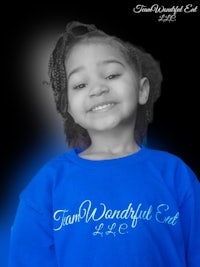 a young girl wearing a blue t - shirt smiling