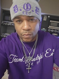 a man wearing a purple t - shirt with a cross on it